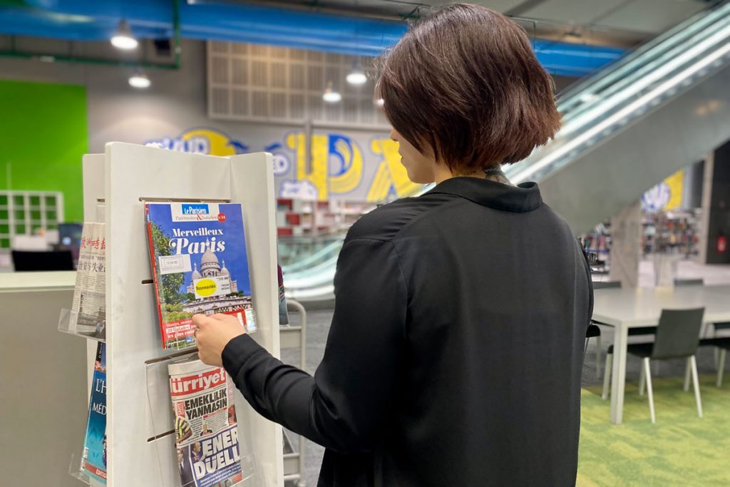 usager consultant un présentoir à journaux