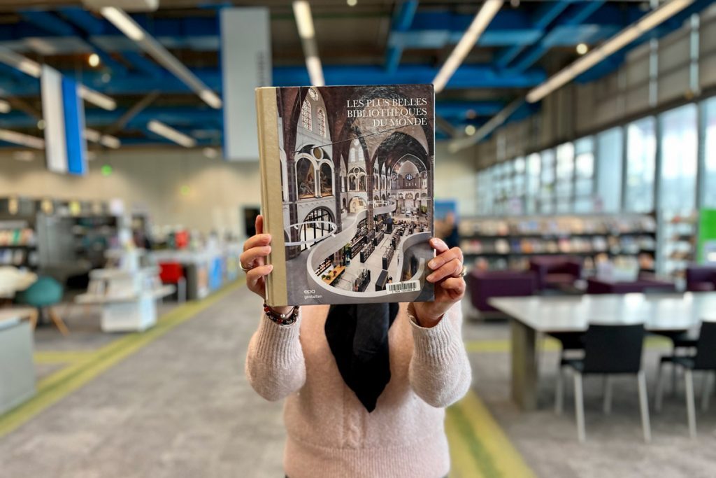 bibliothécaire tenant un ouvrage d'architecture dans les espaces de la bibliothèque