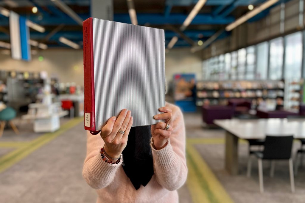 bibliothécaire tenant un ouvrage d'architecture dans les espaces de la bibliothèque
