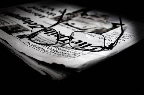 Photo en noir et blanc d'une paire de lunettes posée sur un journal