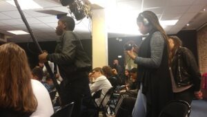 Photographie de jeunes collégiens durant le tournage de l'émission : l'un tenant une perche avec micro, l'autre enregistrant.