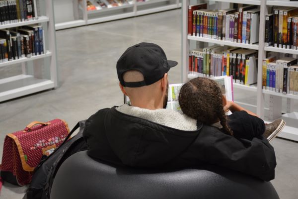Photographie représentant un père et sa fille dans la bibliothèque Assia Djebar