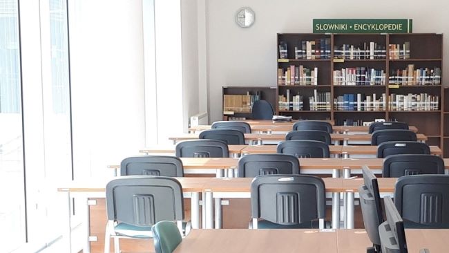 Photographie d'une salle de la bibliothèque vide avec tables et chaises