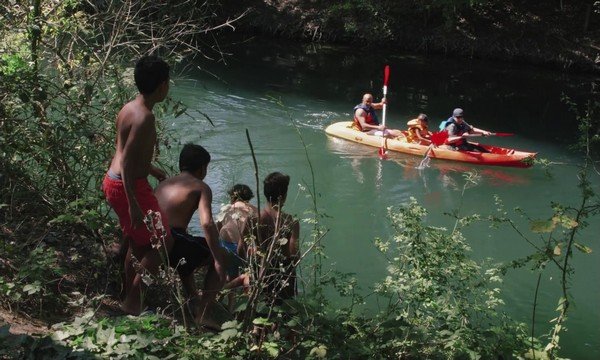 photographie du documentaire : enfants regardant une pirogue passant sur la rivière