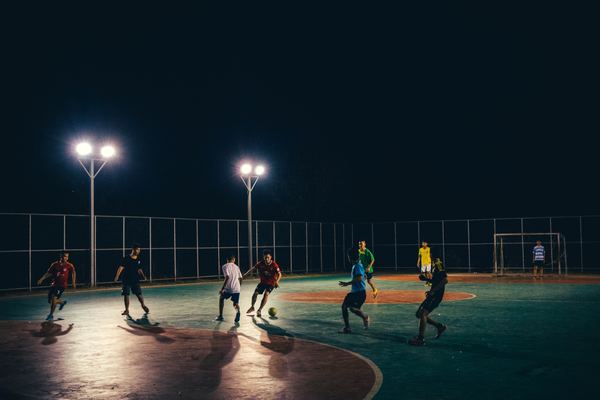 Des jeunes hommes jouent au football la nuit dans un stade