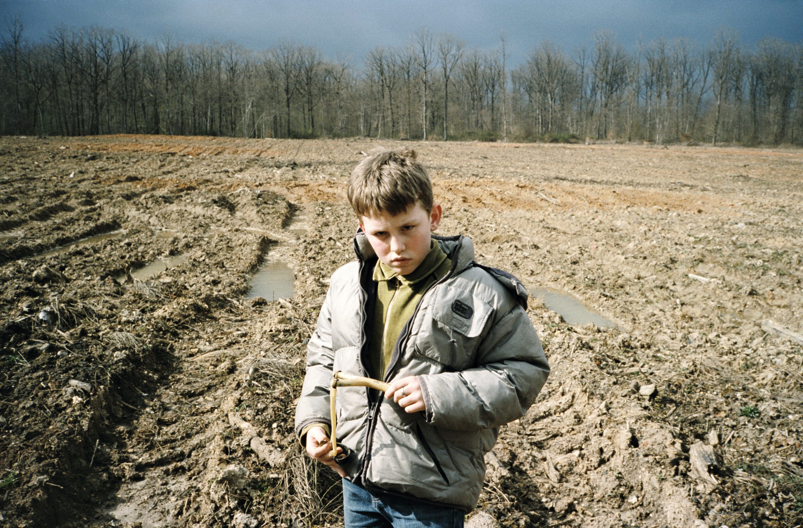 Un garçon fronce les sourcils dans un champ boueux