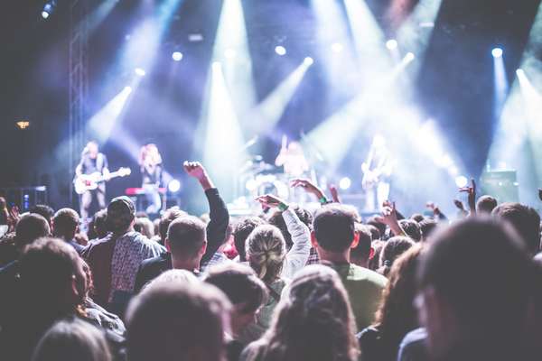 Scène de concert : un groupe de musiciens rock joue devant un public vu de dos