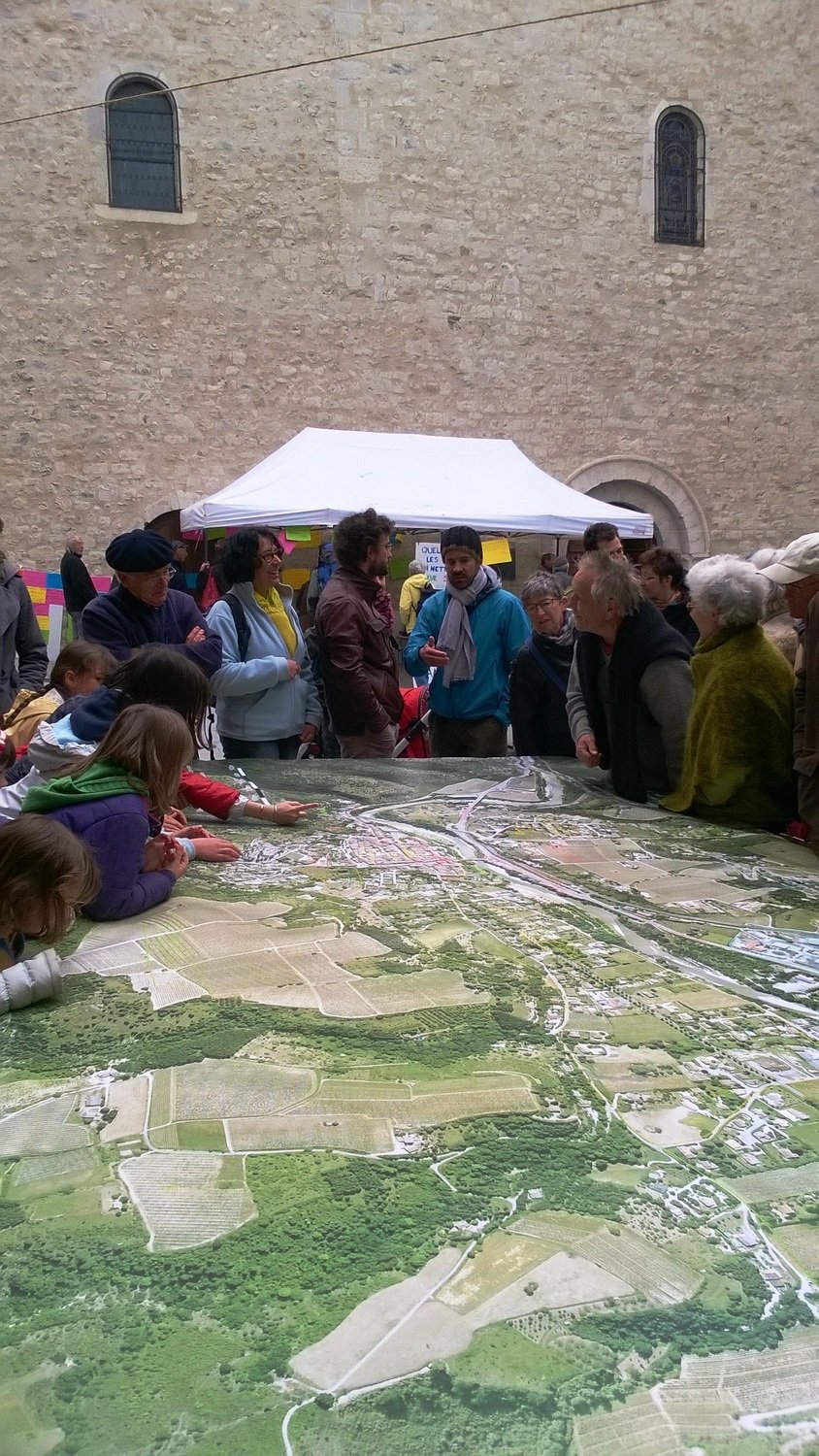 Habitants étudiant la carte de Saillans sur la place de l'église.